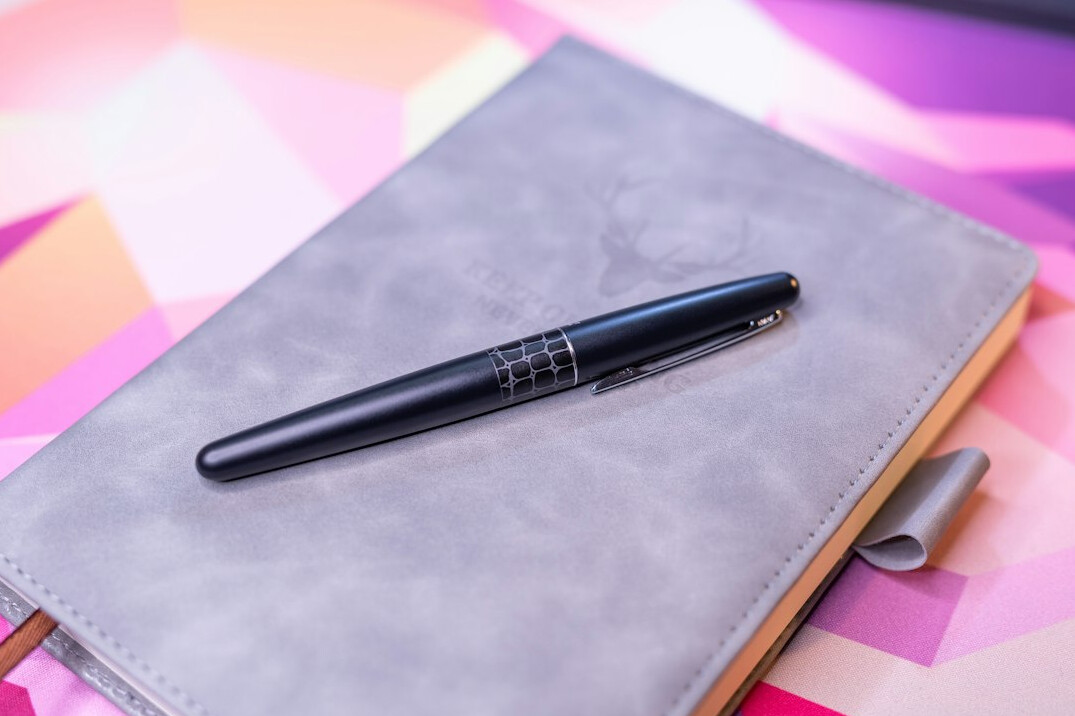 Open leather notebook with fountain pen on an antique desk